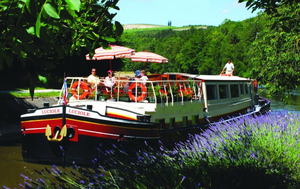 The Luciole cruising past canal banks filled with lavender