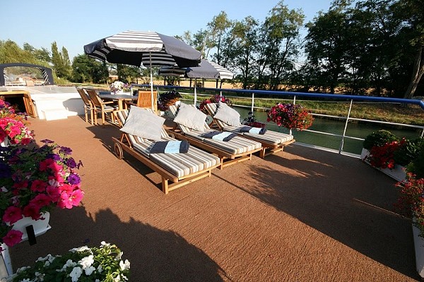 Hotel Barge Saint Louis' sundeck features lounge chairs and a large table for alfresco dining, reading, and relaxation.