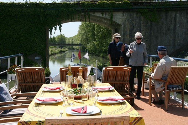 Hotel Barge Saint Louis' sundeck features lounge chairs and a large table for alfresco dining, reading, and relaxation.